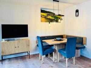 蒂蒂湖-新城Ferienwohnung Niki的一张带蓝色椅子的餐桌和一台电视