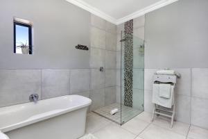 Tokai2 On Lismore Guesthouse的带浴缸和玻璃淋浴间的浴室。