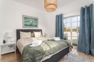 贝纳吉Quiet Spacious House - Swimming Pool的一间卧室配有一张带蓝色窗帘的床和一扇窗户