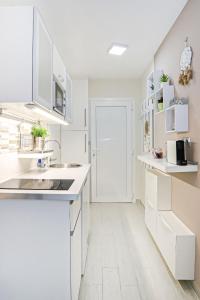 希欧福克Silver Lodge Ezüstpart Apartman的白色的厨房配有白色橱柜和水槽