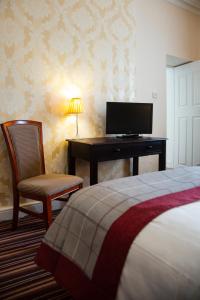 LangholmEskdale Hotel的一间卧室配有一张床和一张书桌及电视