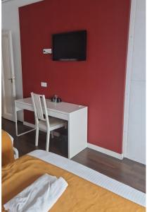 巴塞罗那BruStar Gotic-Centric的一间设有书桌的客房,并在红色的墙上设有一台电视。