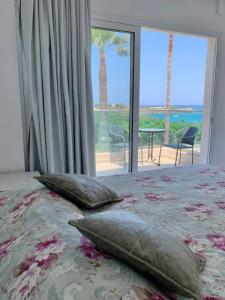 赫索尼索斯Saradari Beach Hotel - Adults Only的卧室配有带枕头的床铺和大窗户