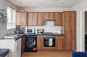 亨顿Albert Duplex Apartment in Hendon NW4的厨房配有木制橱柜、洗衣机和烘干机
