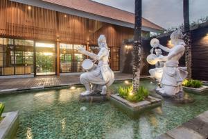 乌布Kanhara Villas Ubud by Pramana Villas的一座建筑前的带雕像的游泳池