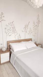 阿尔巴阿尔巴雷勒住宿加早餐旅馆的卧室配有一张铺有白色床单的床,墙上挂着鲜花。