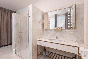 卡罗纳Villa Carona Hotel & Spa的白色的浴室设有水槽和淋浴。