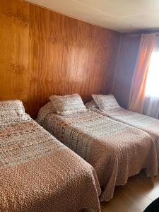 巴拉斯港Cabañas Bosque Sur的木墙客房的两张床