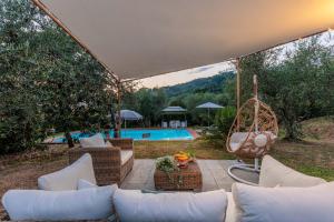 卢卡Villa Dondolino, a Stylish Farmhouse的带沙发、秋千和游泳池的天井