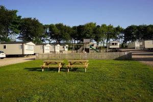 Saint CyrusWrights Retreat 4 Lunan View St Cyrus Caravan Park的两个长椅坐在公园的草地上