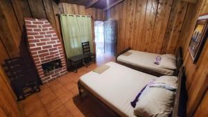 Río ChiquitoHotel de Montaña Buena Vista的带两张床和砖砌壁炉的客房