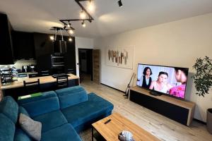 布拉迪斯拉发Lake apartment, 2x free garage, 10 mins to centre的客厅配有蓝色的沙发和平面电视。