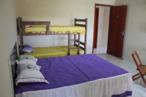 卡波布里奥Kitnet Apto em Cabo Frio RJ - Recanto das Corujas的一间卧室配有两张双层床和紫色床单