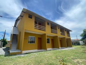 卡波布里奥Kitnet Apto em Cabo Frio RJ - Recanto das Corujas的一座带庭院的大型黄色房屋