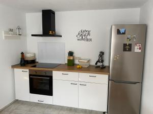 奥贝里德Schwarzwaldglück Apartment的厨房配有白色橱柜和不锈钢冰箱