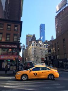 纽约NYC Empire Apartments的一辆黄色的汽车沿着城市街道行驶