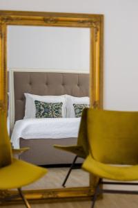 卢布尔雅那City Central的一间卧室配有一张带镜子和椅子的床
