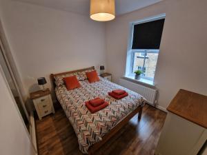 斯基普顿Albert Cottage的一间卧室配有带橙色枕头的床和窗户。