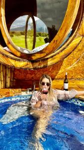莱瓦镇Complejo turístico Magic Bungalow的游泳池里的女人喝一杯葡萄酒