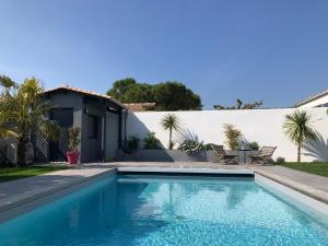 拉罗谢尔Maison M, chambre privée accès jardin piscine et jacuzzi près de La Rochelle的一座房子后院的游泳池