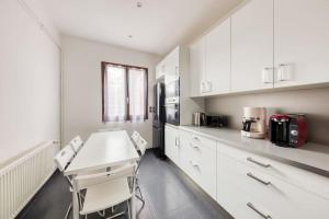布里地区叙西Belle maison Paris/Disney的厨房配有白色橱柜和桌椅