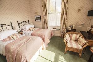 科尼斯顿The Old Rectory的一间卧室设有两张床、一把椅子和一个窗户。