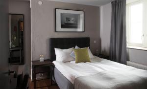 古斯塔堡布洛姆巴拉酒店的一间卧室配有带白色床单和黄色枕头的床。