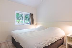 内斯Nesserduinen的白色的卧室设有一张大床和一个窗户
