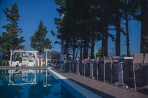 莱瓦贾Hotel Philippos Livadeia的一座房子旁的游泳池,里面设有椅子和树木