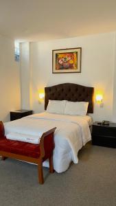 阿亚库乔Hotel San Francisco de Paula Ayacucho的一间卧室配有一张大床和红色长凳
