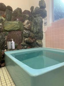 三好市Iya Kankou Ryokan的设有带蓝色浴缸的石墙浴室