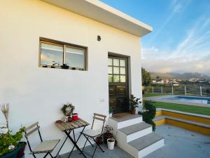 埃尔帕索Vistas directas al volcán y piscina的白色的房子,设有配有桌椅的庭院