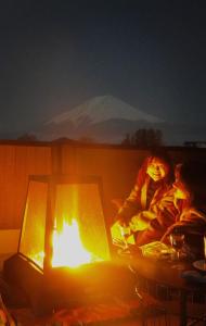 富士河口湖ヴィラ山間堂Panorama Villa BBQ Bonfire Fuji view Annovillas Sankando的坐在火炉旁的女人