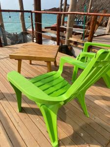 布兰卡滩SUNSET BEACH的甲板上配有两张绿色椅子和一张桌子