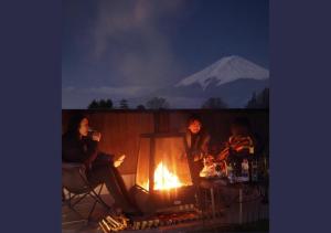 富士河口湖ヴィラ山間堂Panorama Villa BBQ Bonfire Fuji view Annovillas Sankando的三人坐在火炉旁,山底下