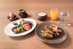 京都TSUGU Kyoto Sanjo by THE SHARE HOTELS的一张桌子,上面放着两盘食物和一碗沙拉