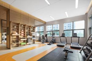 武汉武汉汉口火车站希尔顿惠庭酒店的一个带跑步机和椭圆机的健身房,位于带窗户的房间内