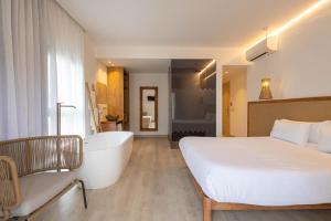 伊维萨镇Play Hotel Ibiza - Adults Only的一间卧室设有一张大床和一个浴缸