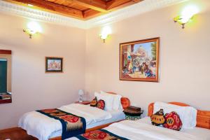 布哈拉萨洛姆旅馆的一间设有两张床的客房,墙上挂着一幅画
