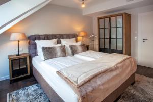 特希尔Hotel Achterum Greetsiel的卧室配有一张带白色床单和枕头的大床。