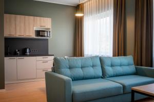 塔林Espak Hostel的一间带蓝色沙发的客厅和一间厨房