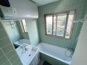 巴黎Entiry apartment, Private rooms in Paris的绿色瓷砖浴室设有浴缸和水槽
