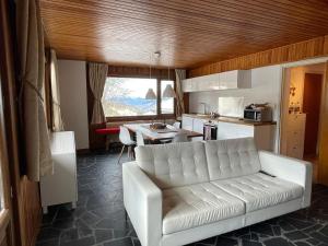 谷雪维尔Lovely Apt Chalet Courchevel 1650的一间带白色沙发的客厅和一间厨房