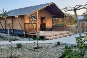 皮特斯迪亚Luxe Safari Lodge Glamping Louloudia的花园内带门廊的豪华帐篷