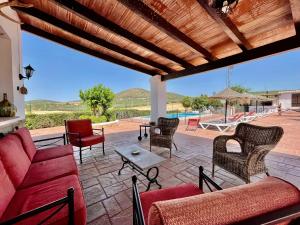 阿尔奇多纳Los Palomos casa rural en el centro de Andalucía的一个带红色沙发、椅子和游泳池的庭院