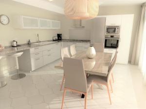 米哈斯科斯塔Miraflores Beachfront Penthouse的厨房配有白色橱柜和木桌及椅子