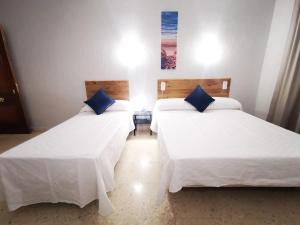 拉克鲁斯Hotel Don Cándido的配有白色床单和蓝色枕头的客房内的两张床