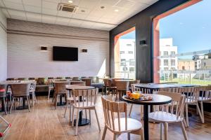 布瓦达西B&B HOTEL Bois d'Arcy Saint Quentin en Yvelines的餐厅设有桌椅和平面电视。
