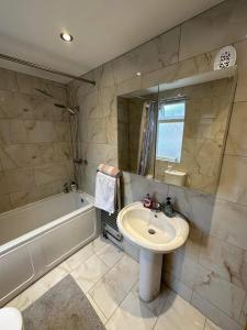 卢顿Luton Town House Near AIRPORT的浴室配有盥洗盆、镜子和浴缸