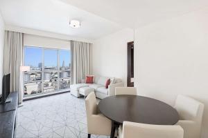 迪拜Hyatt Place Dubai Jumeirah的客厅配有桌椅和大窗户